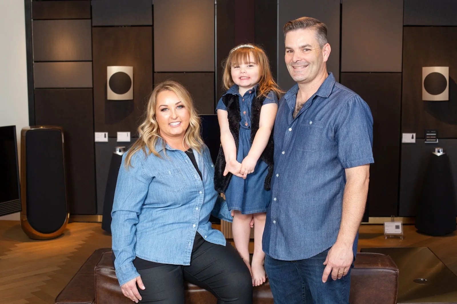 The Watt family seated in the Scottsdale showroom with Beolab speakers on the wall behind them