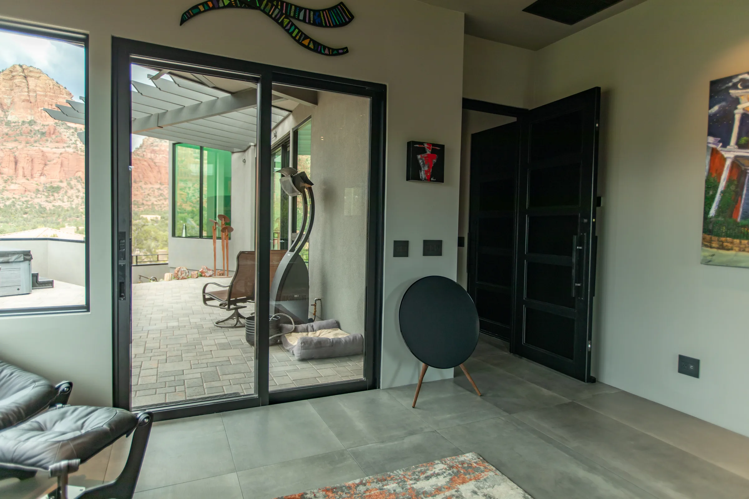 Bang & Olufsen Beosound A9 speaker beside a black-framed sliding glass door with Sedona red rocks beyond