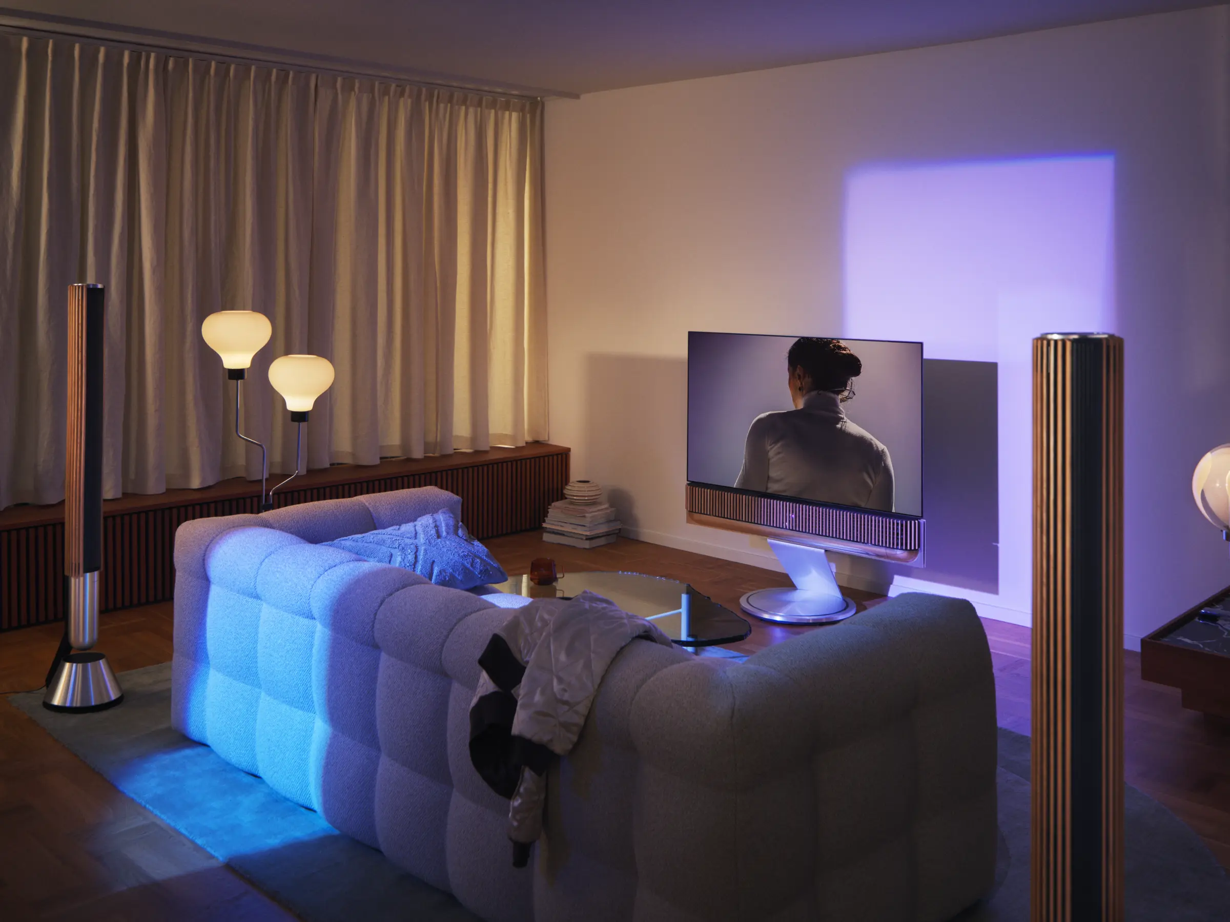 Bang & Olufsen screen with the Beosound Theatre soundbar between two Beolab 28 speakers in an evening living room — Bang & Olufsen interior