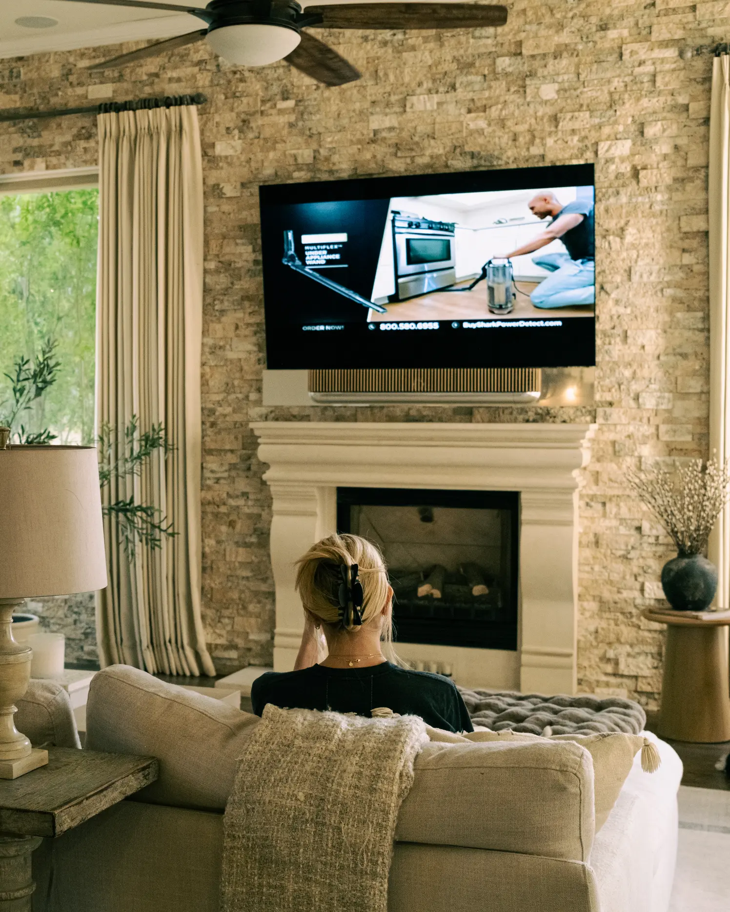 Wall-mounted television and Beosound Theatre soundbar above a stone fireplace, watched from the sofa — Watt Integration project home