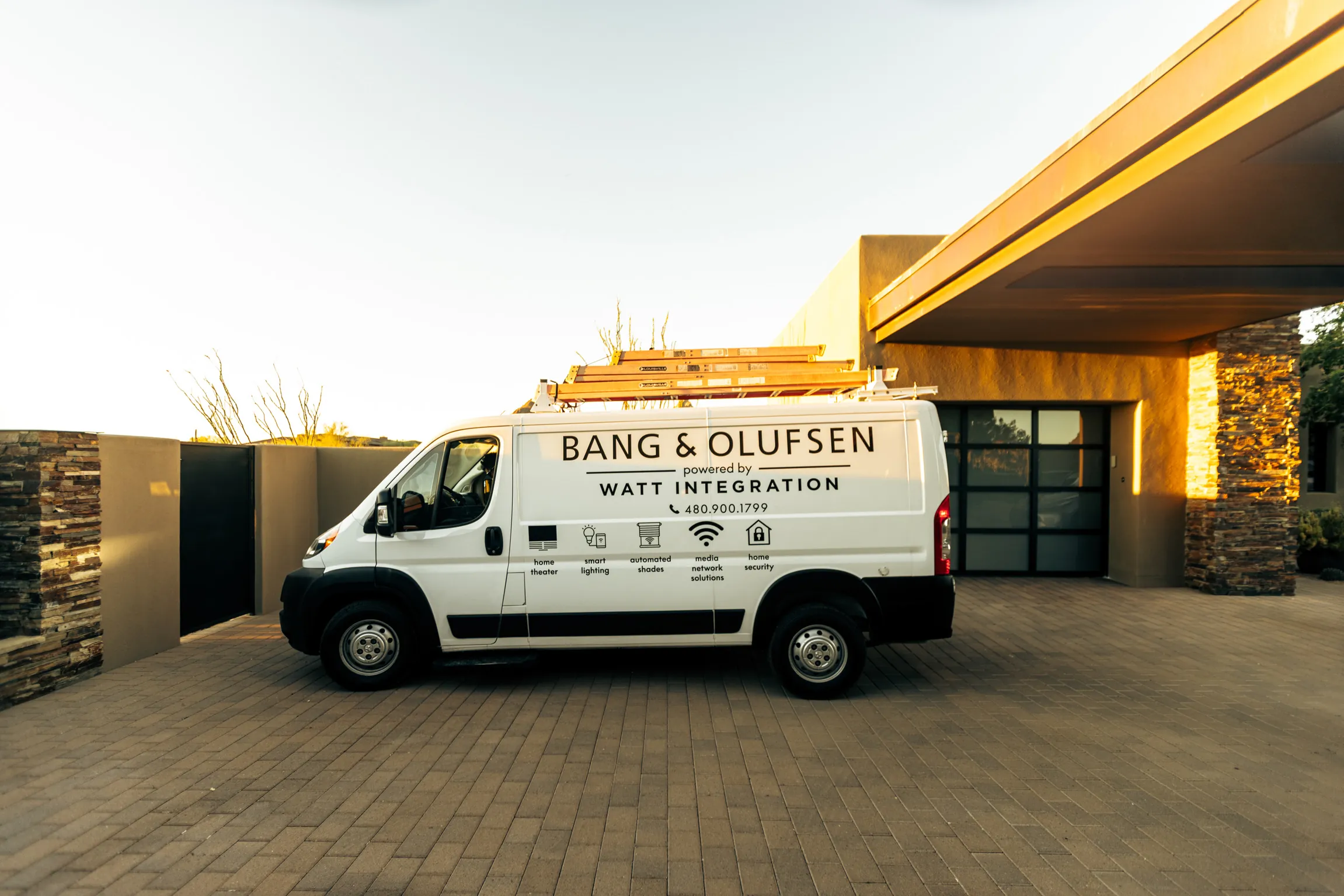 Bang & Olufsen powered by Watt Integration branded van parked at a desert-modern Scottsdale home at golden hour
