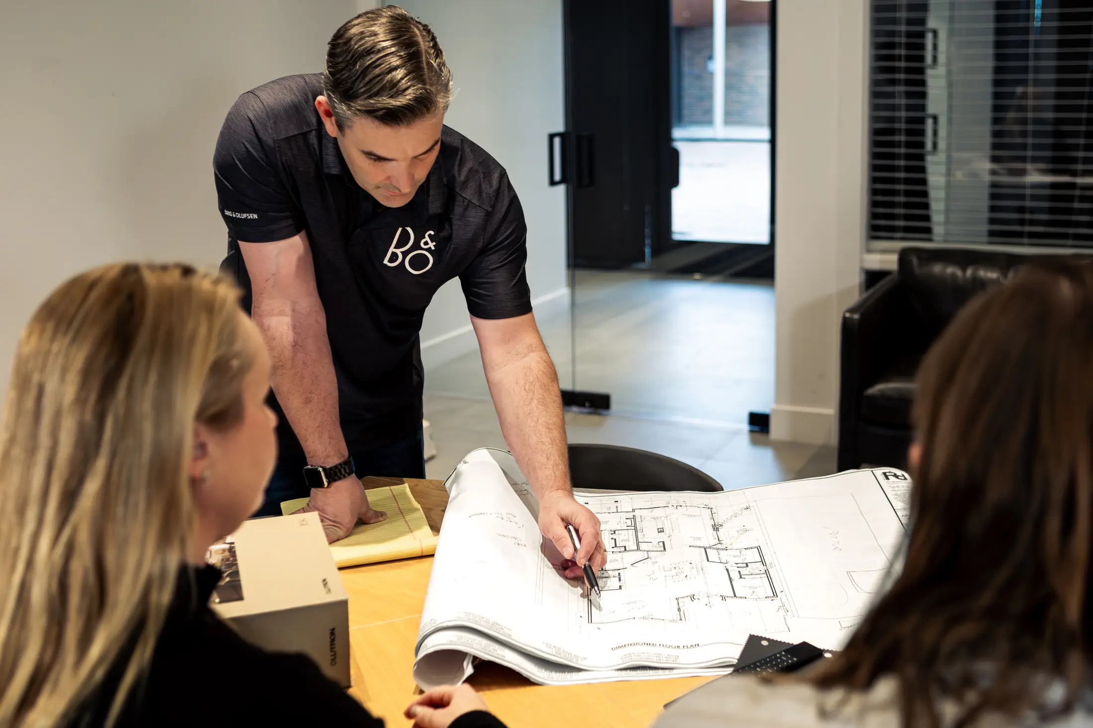 Bryan Watt standing at a table in the Scottsdale showroom, walking two clients through a set of floor plans