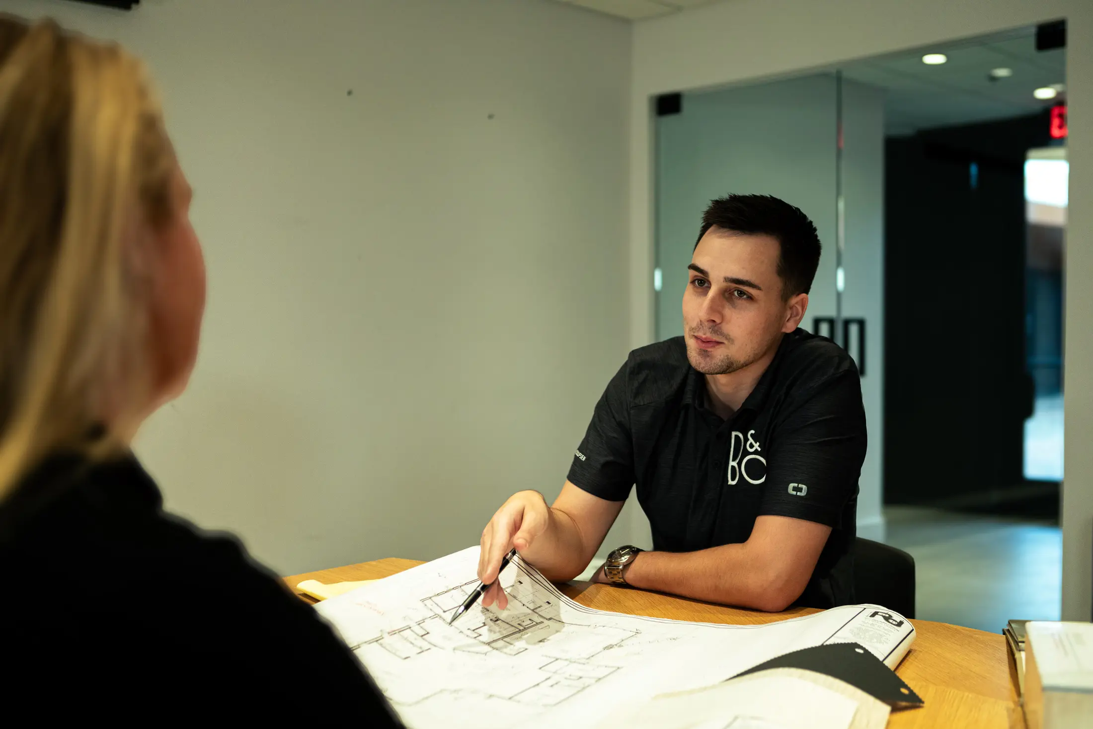 Dan Wolf pointing to a detail on a floor plan while a client looks on across the table