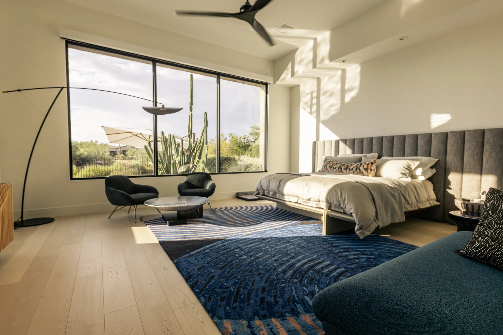 Primary bedroom picture window with motorized shades raised, desert sun pouring in