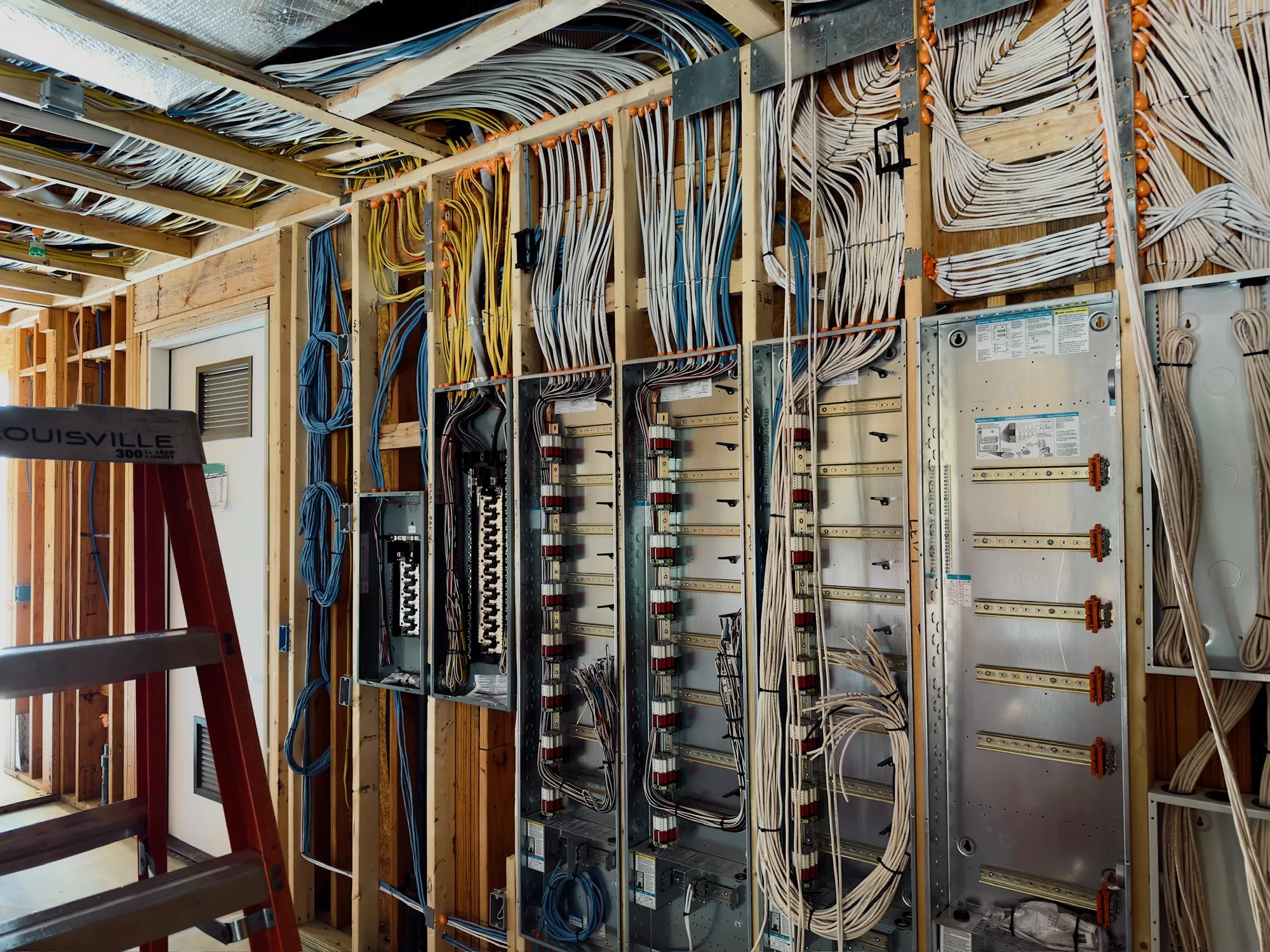 Structured-wiring pre-wire at rough-in — combed cable runs and mounted panels across an open-framed wall