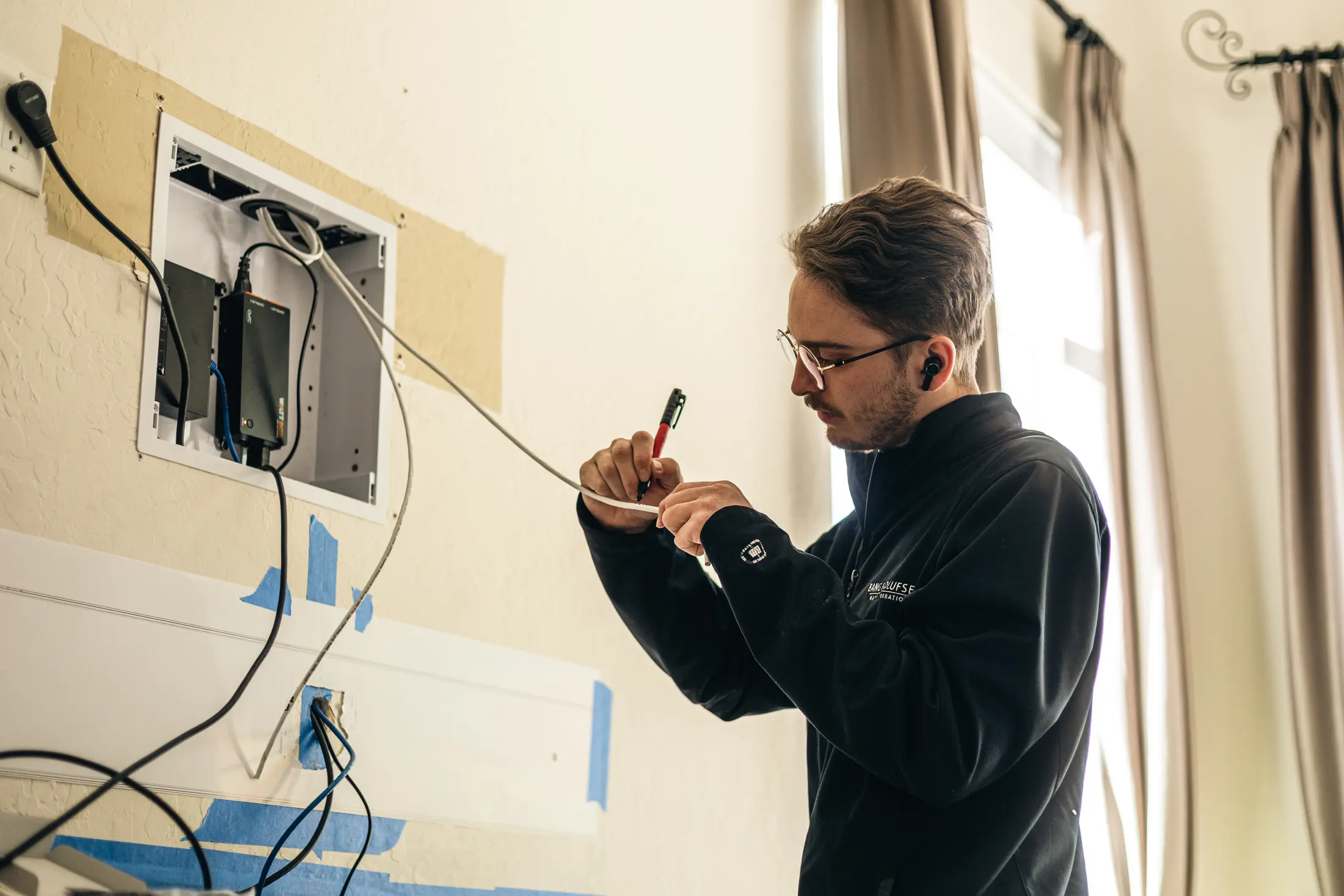 Watt Integration technician wiring a recessed low-voltage network panel at a client install