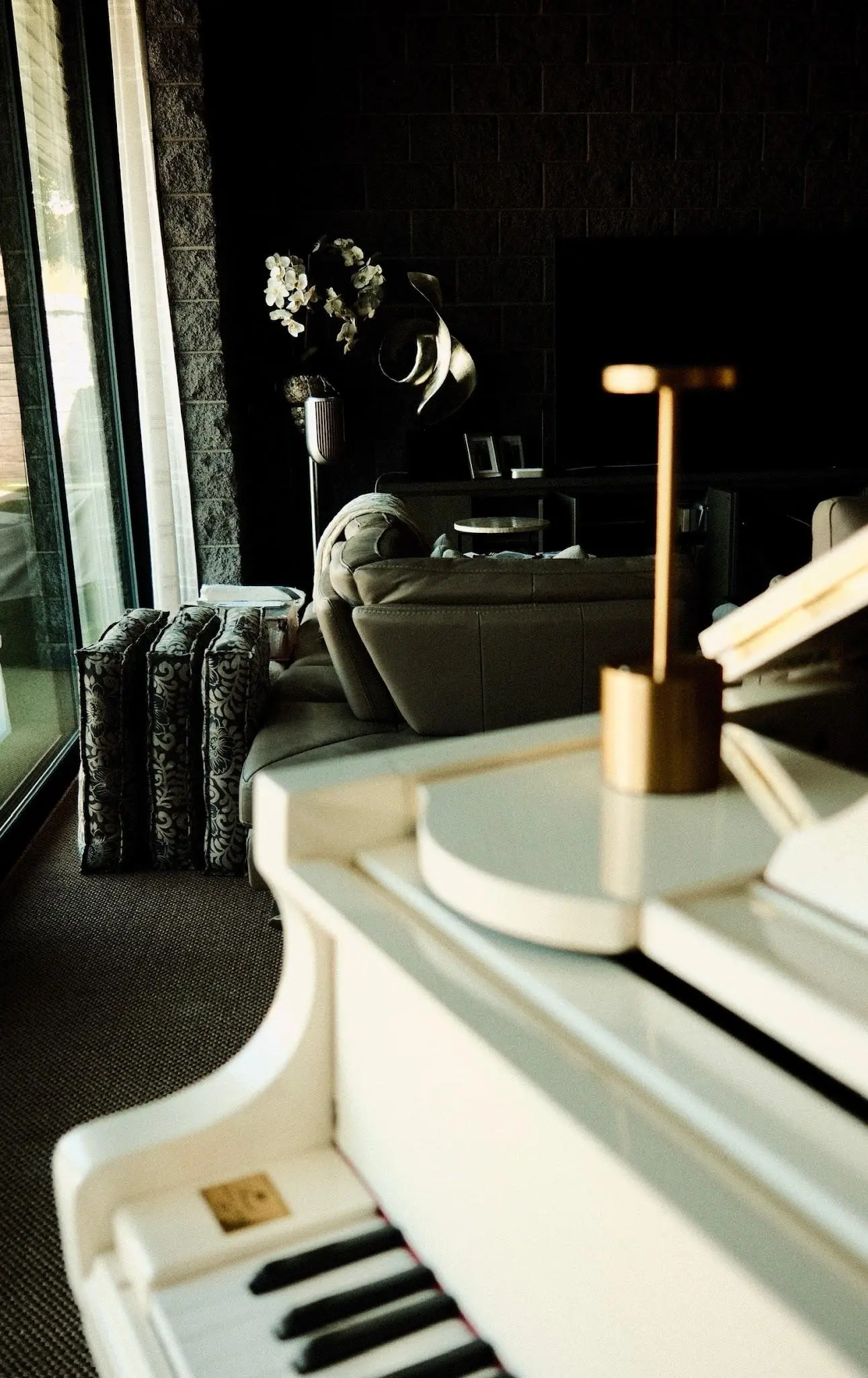 White grand piano in the living room of the Fogerty home, the media wall beyond — from the whole-home upgrade story