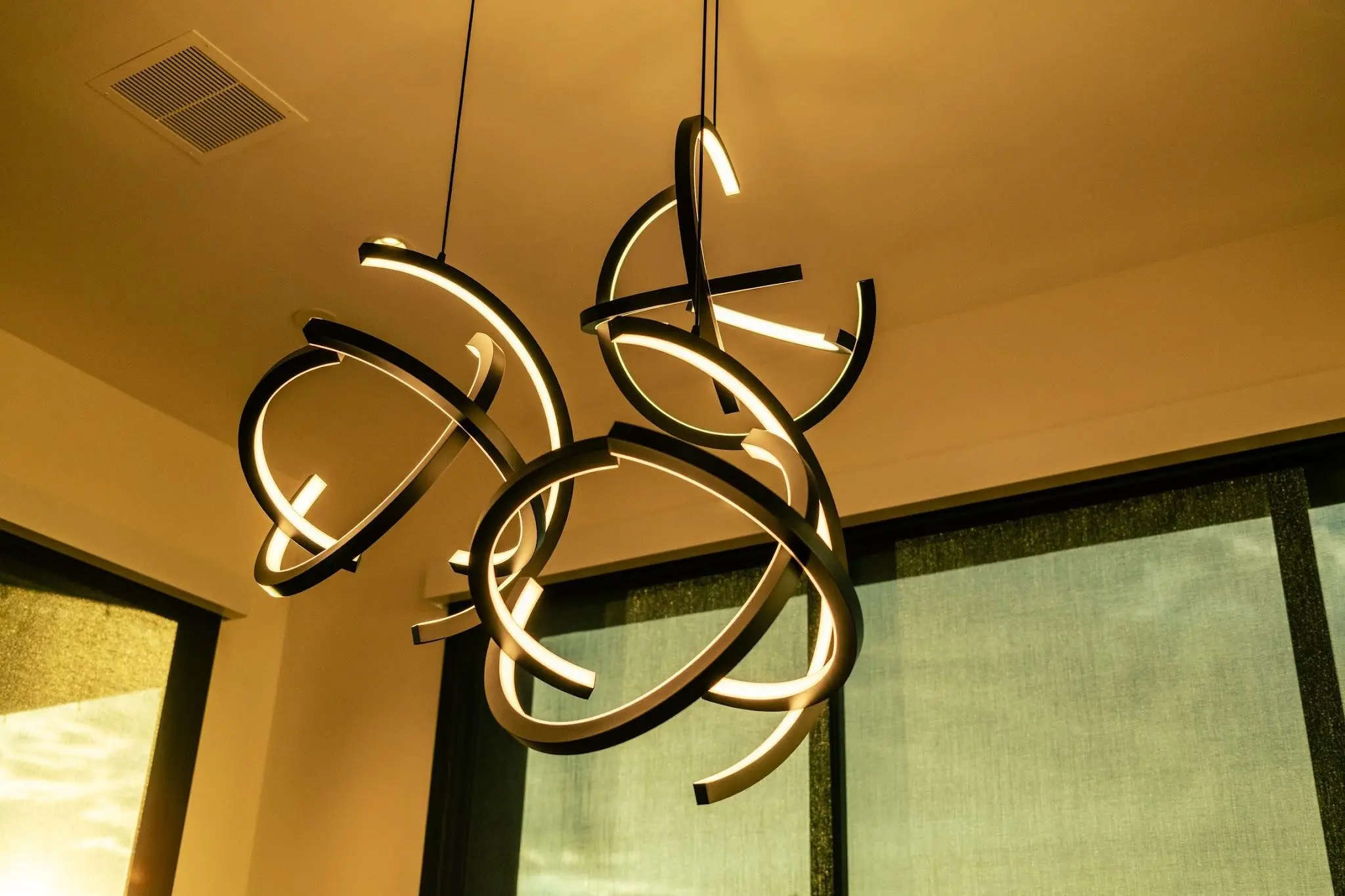 Sculptural ring chandelier over the dining space of the connected Scottsdale home, shades drawn against the afternoon sun